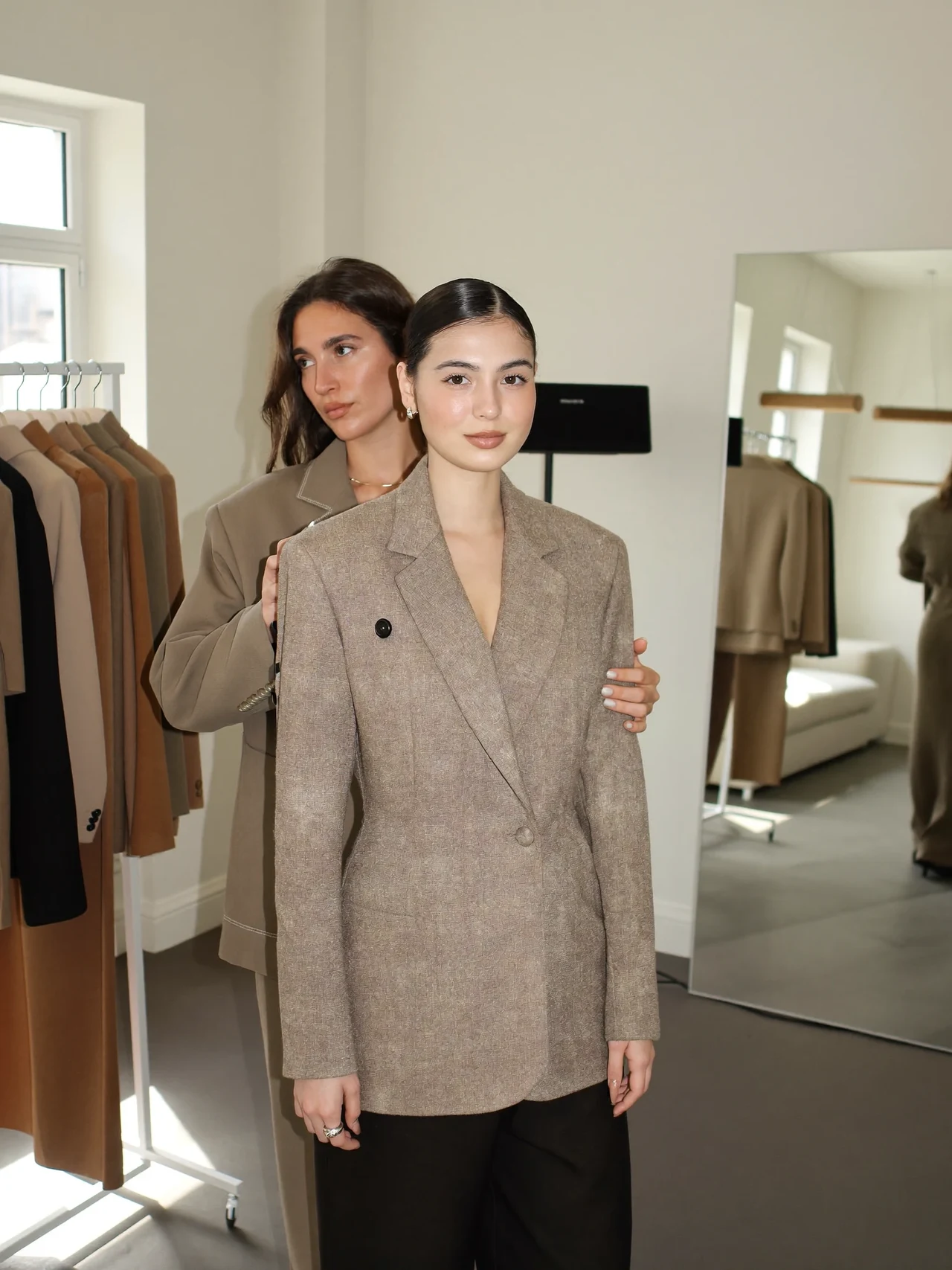 Helles Stylingstudio mit Kleiderstange, Spiegel und Stylistin bei der Anprobe