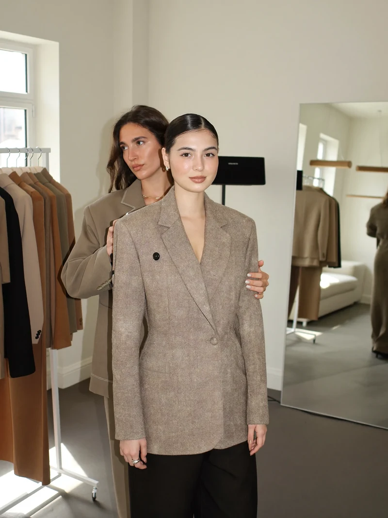 Helles Stylingstudio mit Kleiderstange, Spiegel und Stylistin bei der Anprobe